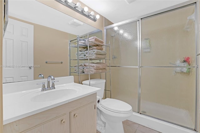 bathroom featuring tile patterned flooring, vanity, toilet, and a shower with shower door