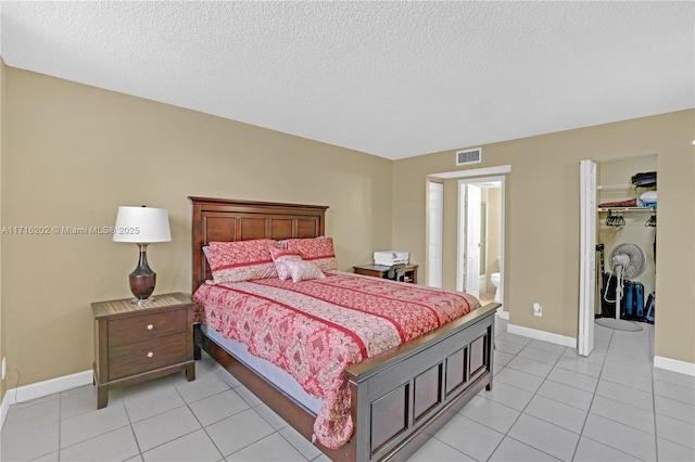 bedroom with ensuite bath, a closet, light tile patterned floors, and a textured ceiling