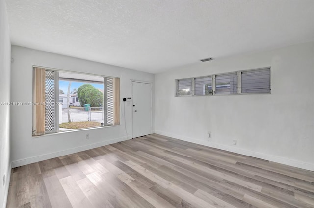 spare room with light hardwood / wood-style flooring and a textured ceiling