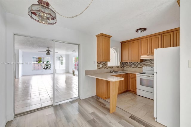 kitchen featuring kitchen peninsula, tasteful backsplash, white appliances, ceiling fan, and sink