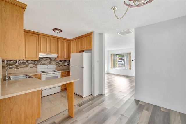 kitchen with kitchen peninsula, tasteful backsplash, white appliances, sink, and light hardwood / wood-style floors