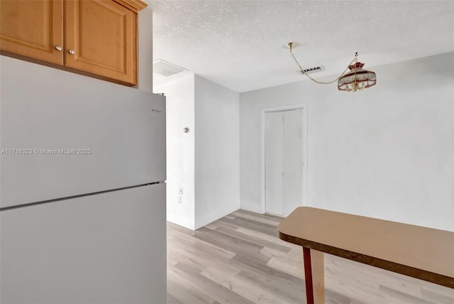 kitchen featuring light hardwood / wood-style flooring, white fridge, and a textured ceiling