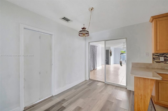 unfurnished dining area with ceiling fan and light hardwood / wood-style floors