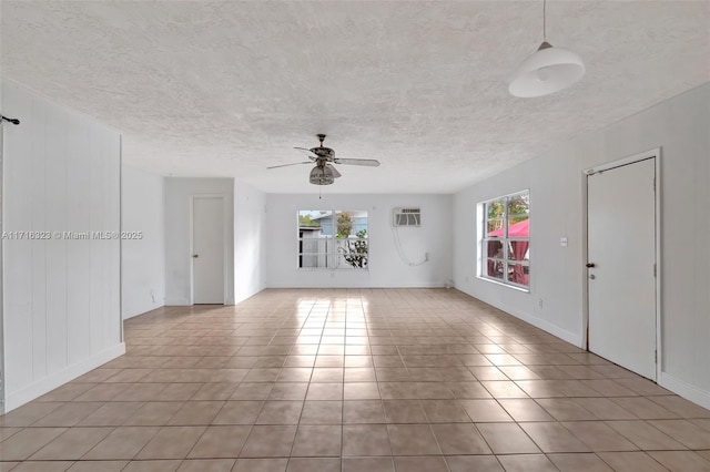 unfurnished room with ceiling fan, a wall unit AC, light tile patterned floors, and a wealth of natural light