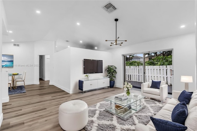 living room featuring a chandelier, light wood-type flooring, and vaulted ceiling