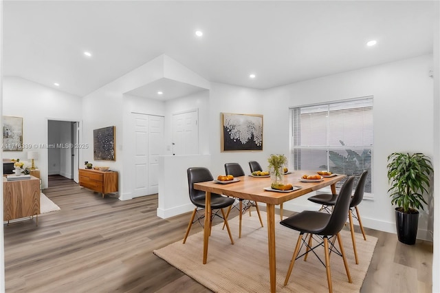 dining space with vaulted ceiling and light hardwood / wood-style floors