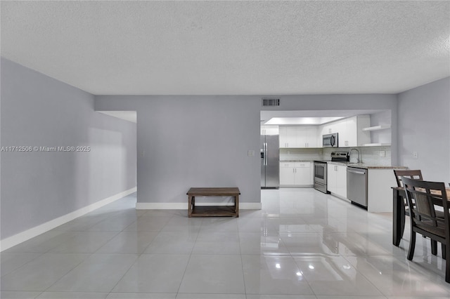 interior space with sink, light tile patterned flooring, decorative backsplash, white cabinets, and appliances with stainless steel finishes