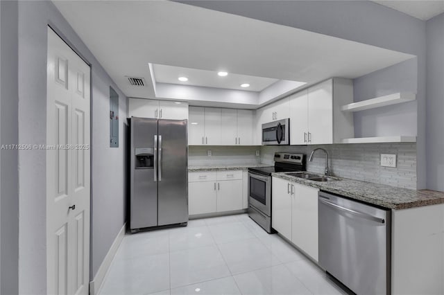 kitchen with appliances with stainless steel finishes, backsplash, a tray ceiling, sink, and white cabinetry