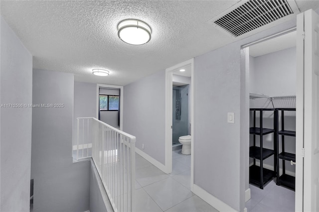 hallway with light tile patterned floors and a textured ceiling