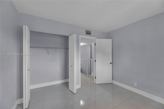 unfurnished bedroom with a textured ceiling, a closet, and light tile patterned flooring