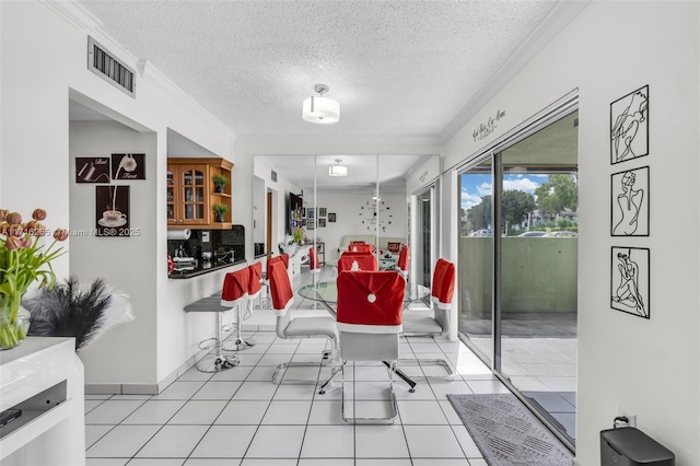 tiled dining space with a textured ceiling and ornamental molding