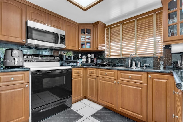 kitchen with light tile patterned floors, black range with electric stovetop, a wealth of natural light, and sink