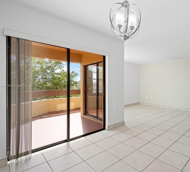 tiled spare room featuring a chandelier