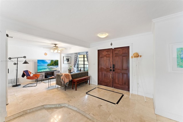 foyer entrance with crown molding and ceiling fan