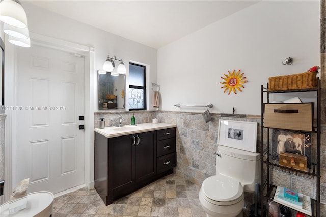 bathroom with vanity, tile walls, and toilet