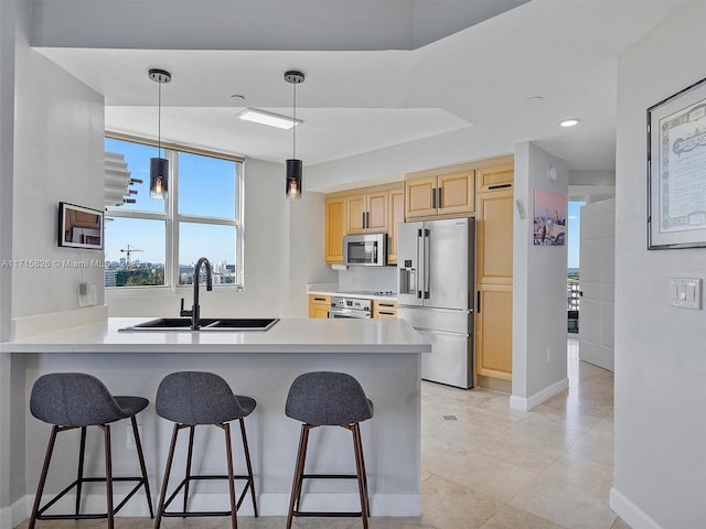 kitchen with sink, light brown cabinets, stainless steel appliances, kitchen peninsula, and decorative light fixtures