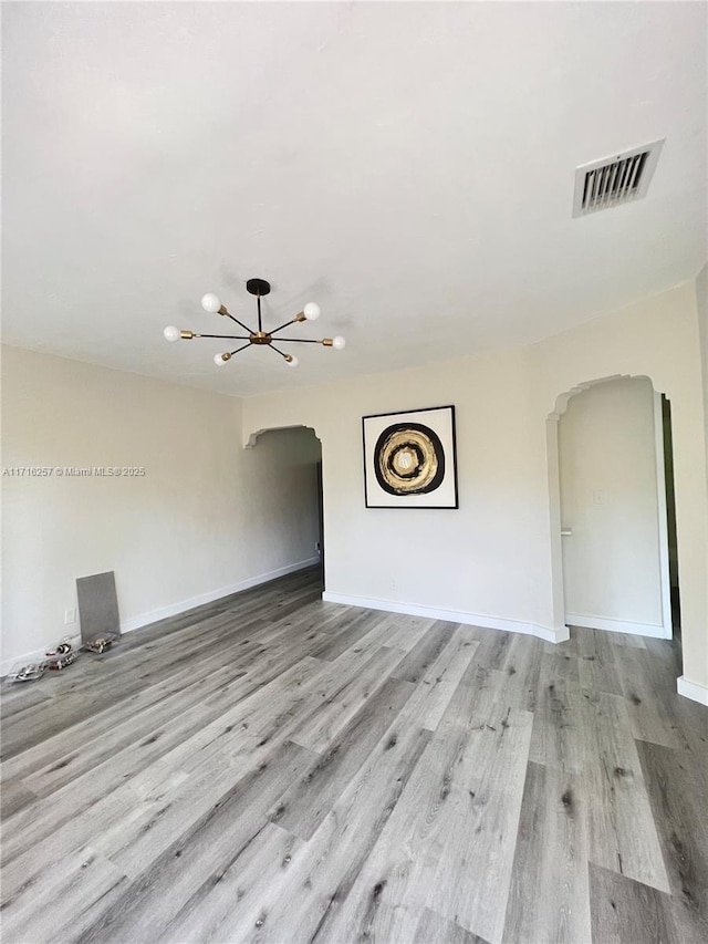 spare room with a chandelier and light hardwood / wood-style floors