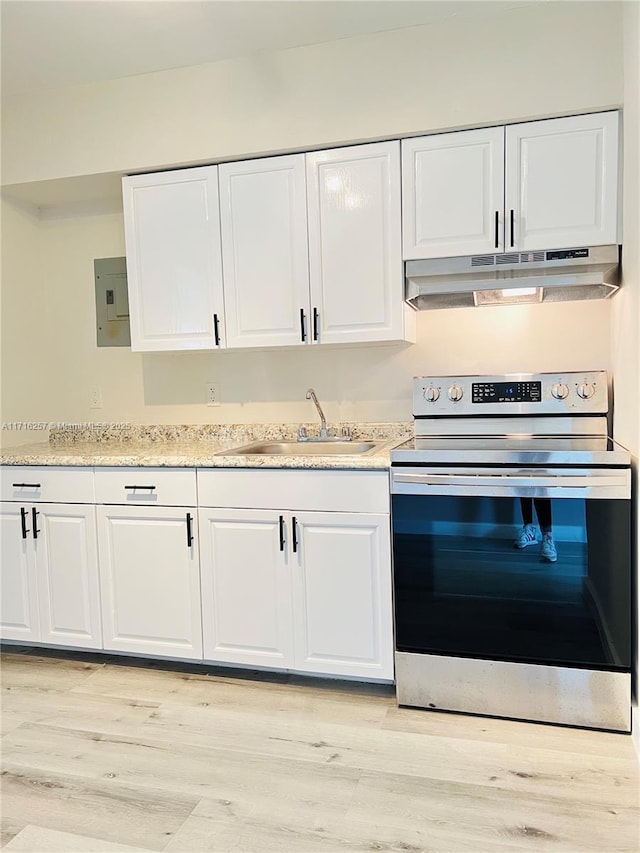 kitchen featuring white cabinets, light wood-type flooring, stainless steel electric range oven, and sink