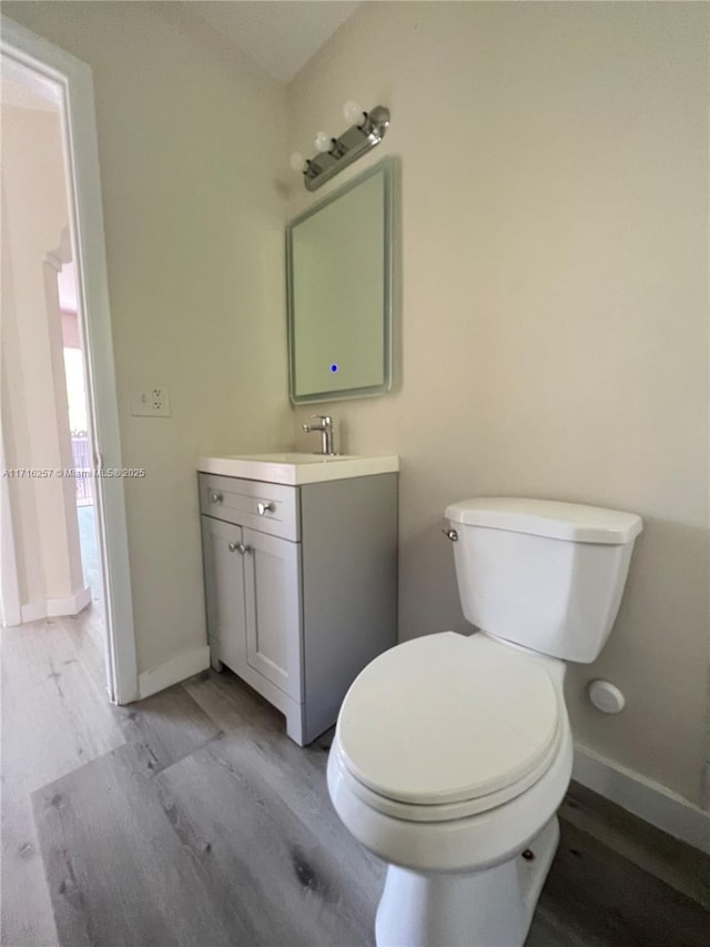 bathroom with vanity, wood-type flooring, and toilet