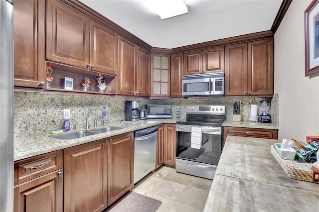 kitchen featuring sink, light tile patterned floors, appliances with stainless steel finishes, tasteful backsplash, and light stone counters