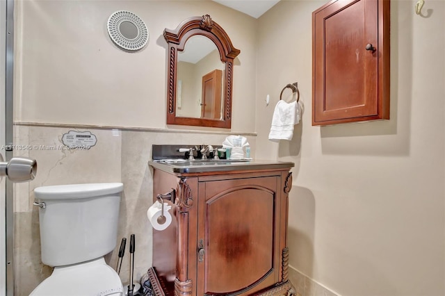 bathroom with vanity, tile walls, and toilet