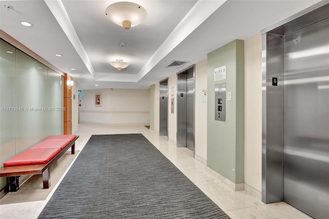 corridor featuring a tray ceiling and elevator