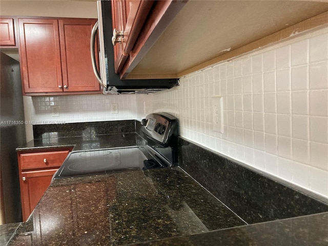 details featuring black range with electric stovetop, backsplash, dark stone counters, and fridge