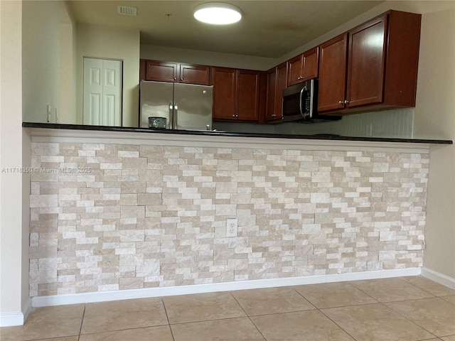 kitchen featuring kitchen peninsula, appliances with stainless steel finishes, and light tile patterned floors