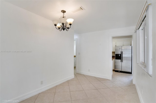 empty room with a notable chandelier and light tile patterned floors