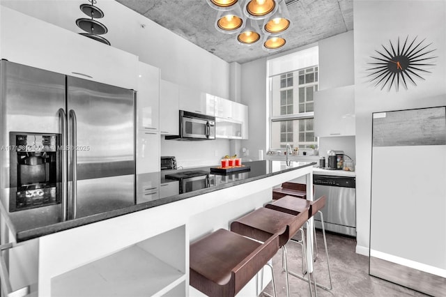 kitchen featuring white cabinets, stainless steel appliances, kitchen peninsula, and a breakfast bar area