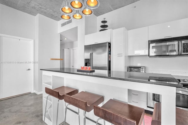 kitchen with a kitchen bar, white cabinets, and appliances with stainless steel finishes