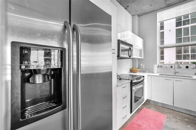 kitchen featuring white cabinetry, sink, appliances with stainless steel finishes, and concrete floors