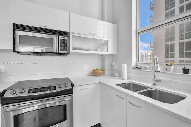 kitchen with stainless steel electric range, white cabinetry, and sink