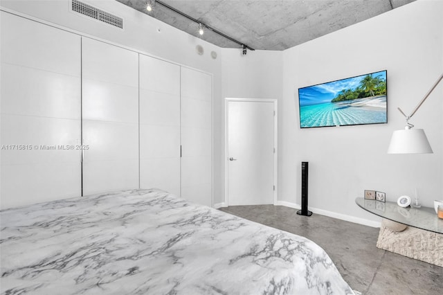 bedroom with concrete flooring and track lighting