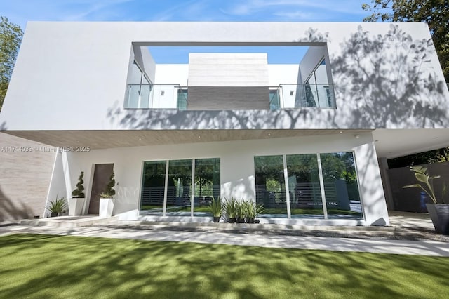 rear view of property with stucco siding and a lawn