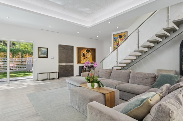 living room with a tray ceiling, stairs, wood finished floors, and recessed lighting
