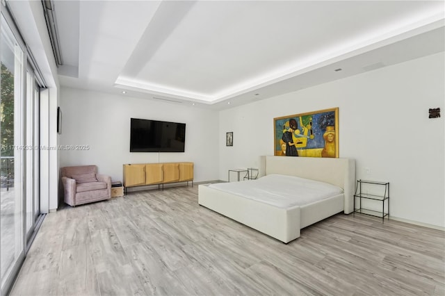 unfurnished bedroom featuring light wood-type flooring and a raised ceiling