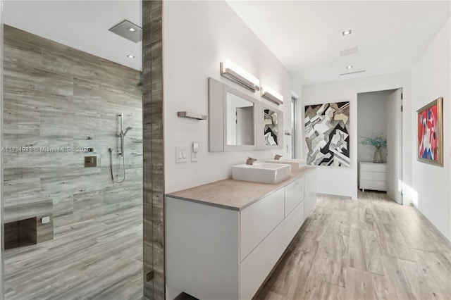 bathroom featuring a wall unit AC, vanity, walk in shower, and wood finished floors