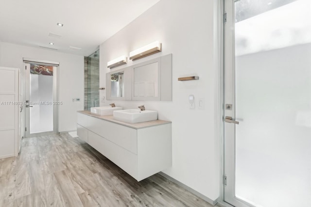 full bath featuring double vanity, an enclosed shower, wood finished floors, and a sink