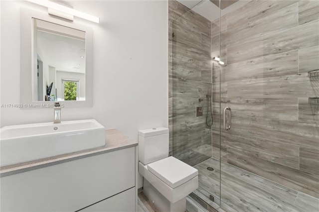 bathroom featuring vanity, a shower stall, and toilet