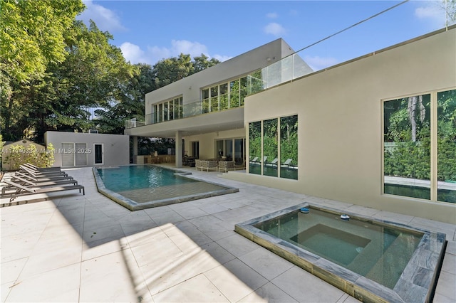 outdoor pool with an in ground hot tub and a patio area
