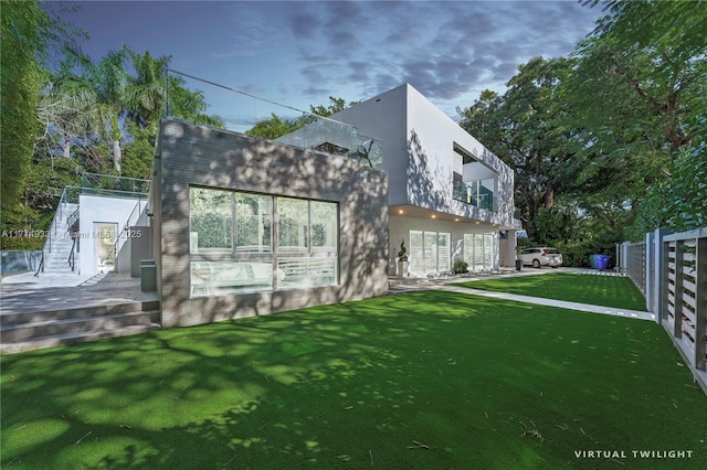 back of property with stucco siding, fence, and a yard