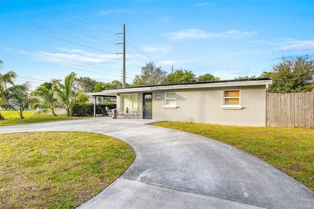 ranch-style home featuring a carport and a front yard