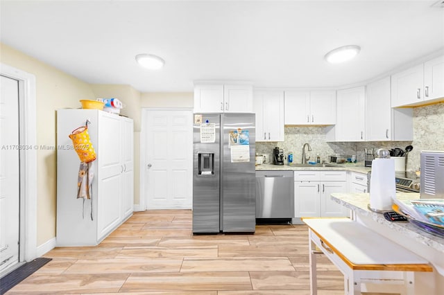 kitchen featuring tasteful backsplash, white cabinetry, sink, and appliances with stainless steel finishes