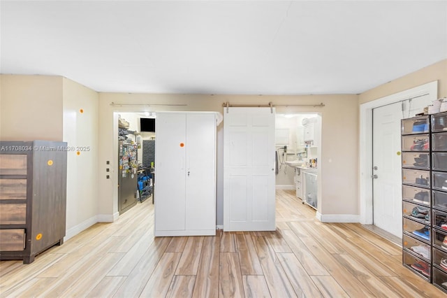 kitchen featuring a barn door, light wood-type flooring, and white cabinetry