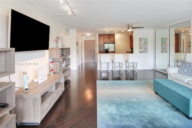 living room featuring rail lighting, dark wood-type flooring, ceiling fan, and crown molding