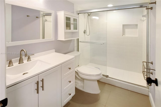 bathroom featuring tile patterned flooring, vanity, toilet, and a shower with shower door