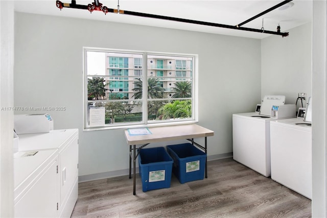 laundry area with independent washer and dryer, a wealth of natural light, and light hardwood / wood-style flooring