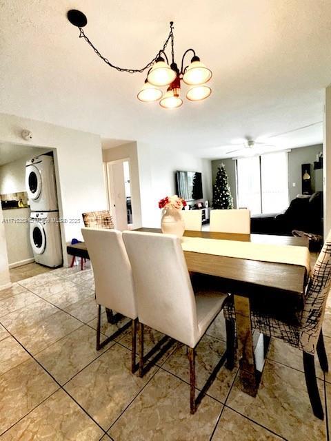 dining room with ceiling fan with notable chandelier and stacked washer and clothes dryer