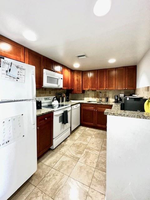 kitchen with white appliances, tasteful backsplash, and light stone counters